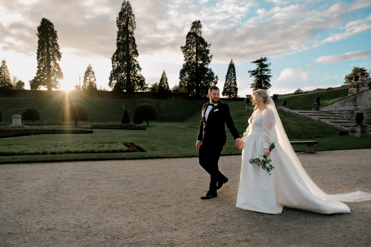 bride and groom walking in the sunset at Powerscourt Estate and gardens