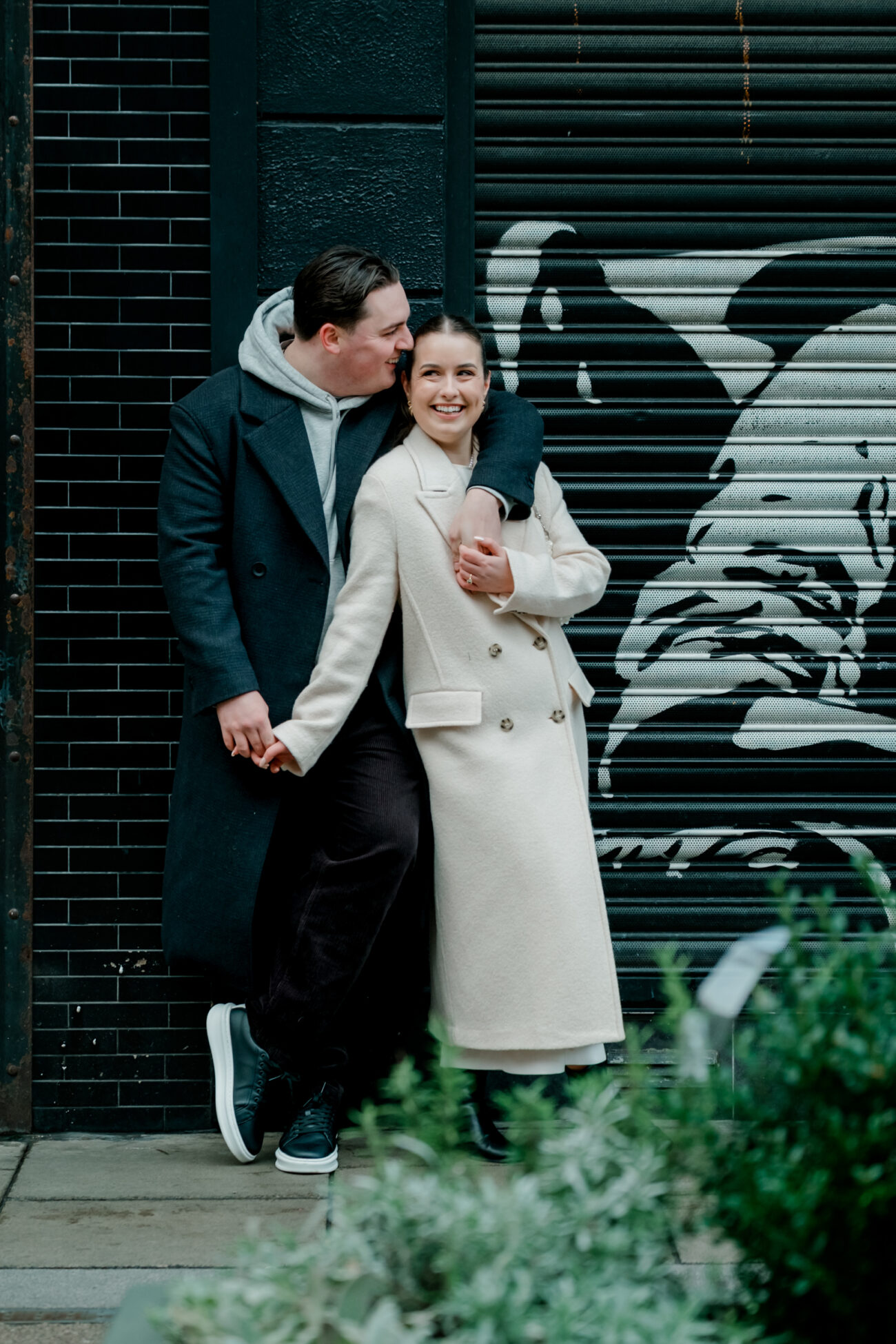 Couple cuddling and leaving against a wall in Dublin City