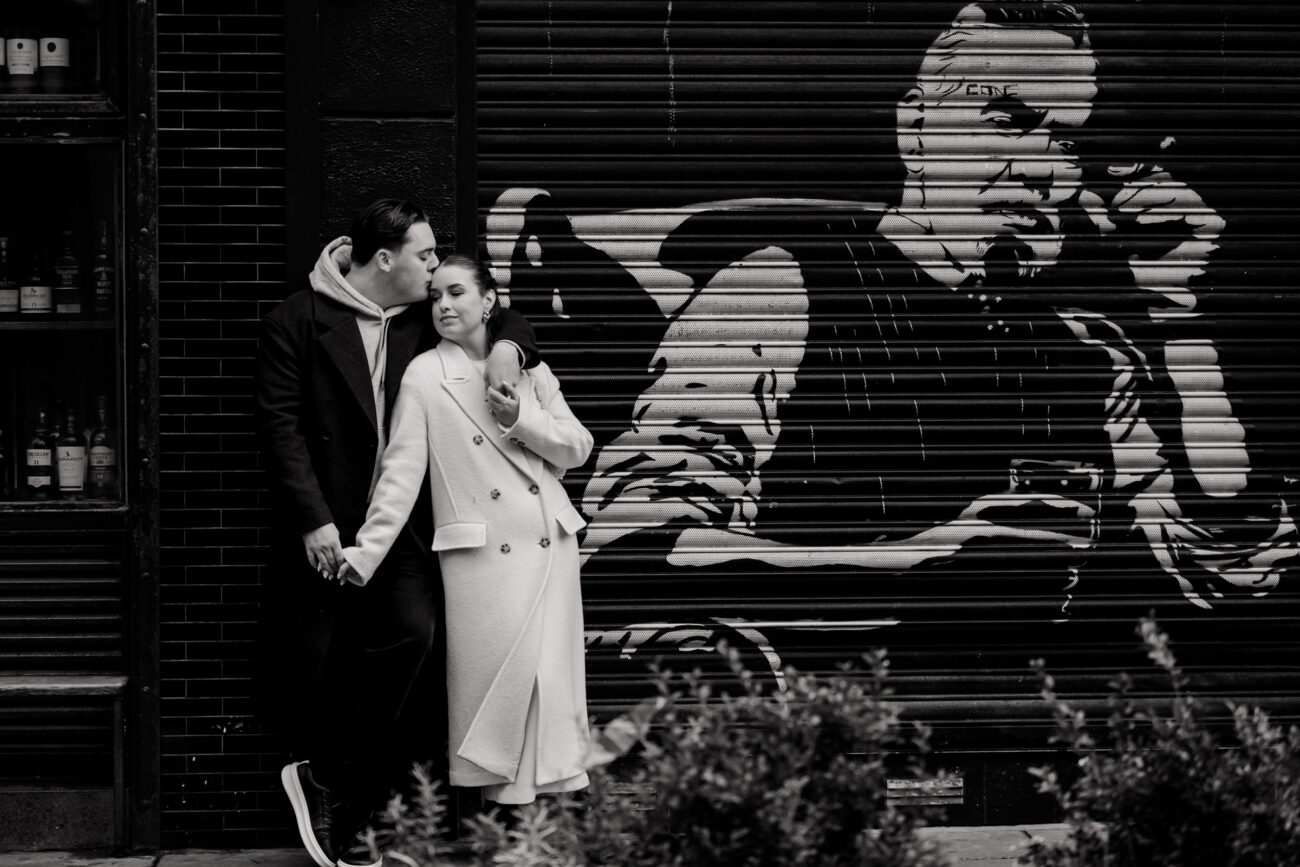 Couple hugging and leaning against a graffiti wall in Dublin