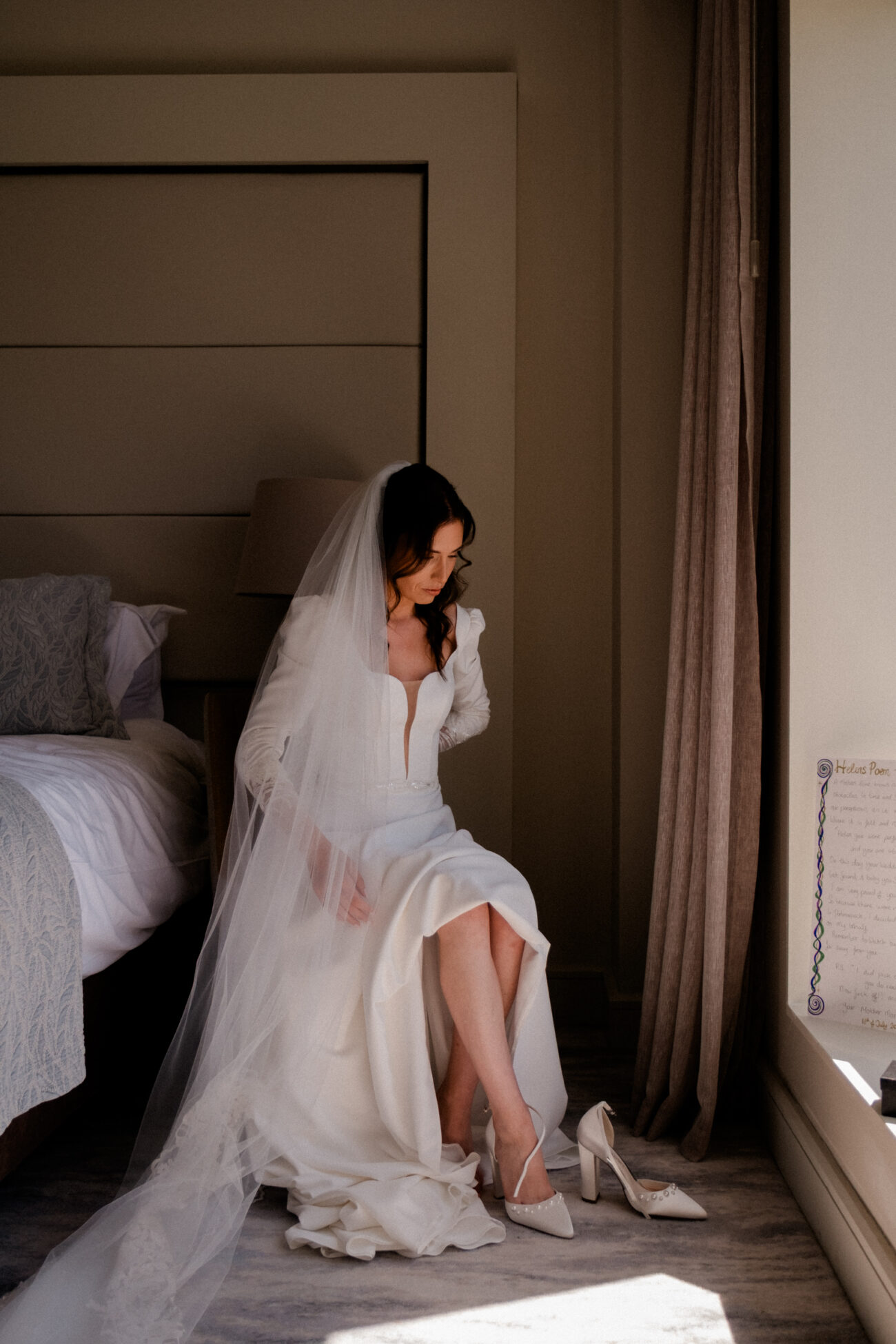 Bride in her wedding dress at the window during bridal prep at Portmarnock Resort