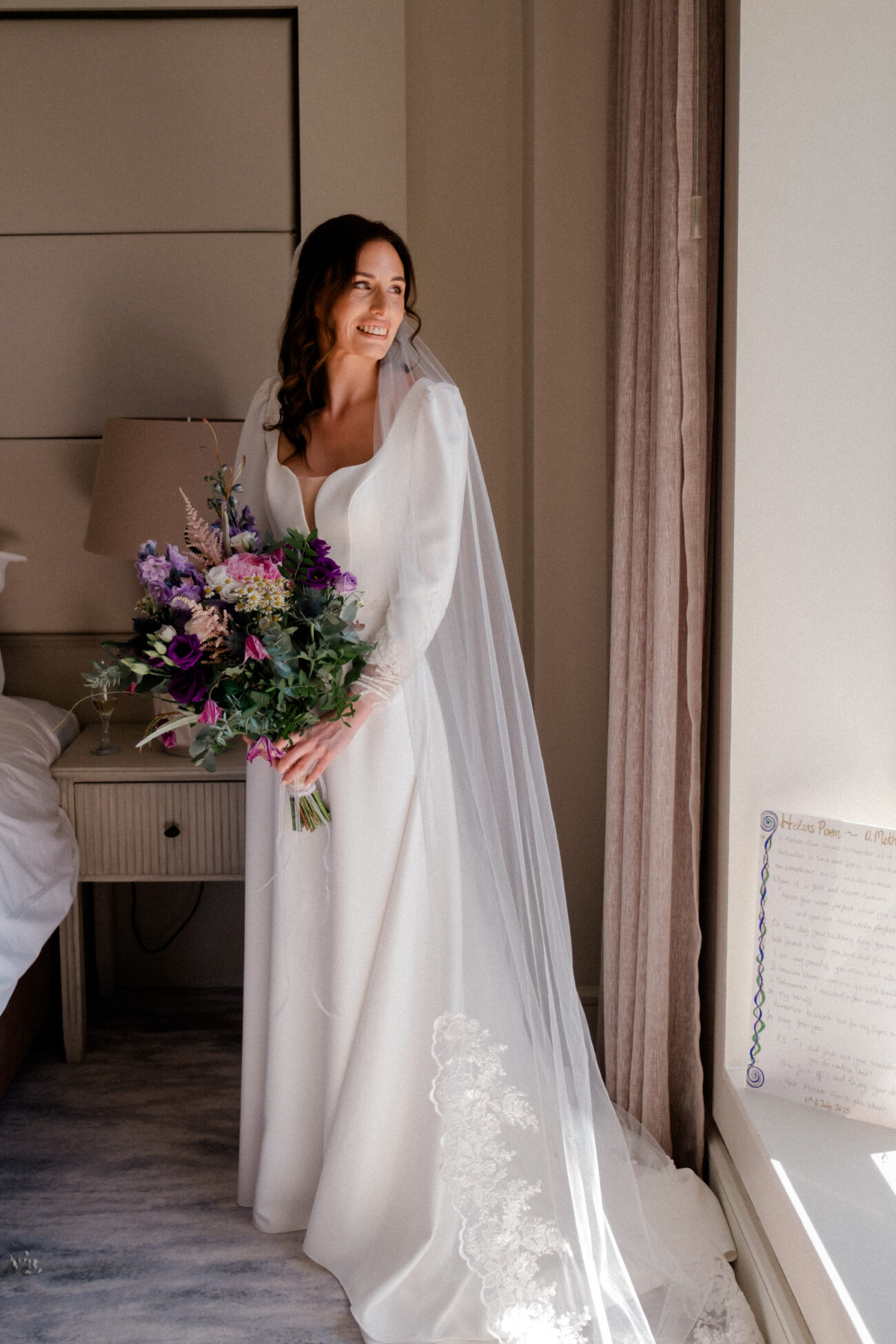 Bride in her wedding dress at the window during bridal prep at Portmarnock Resoert