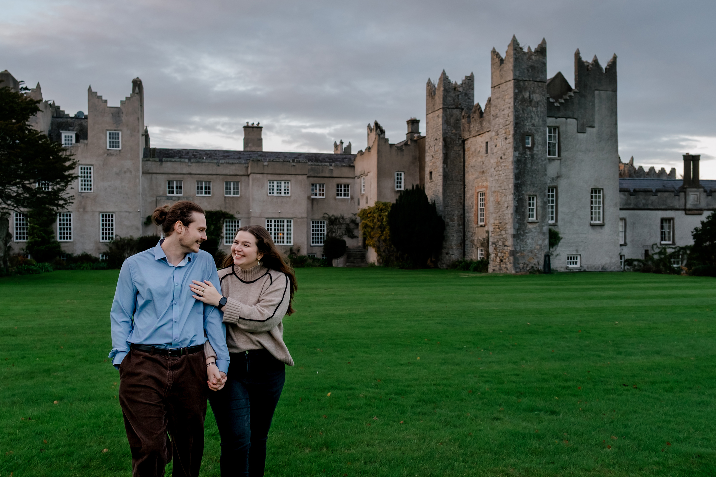Couple walking and smiling after a secret proposal at Howth Castle, Howth, Dublin
